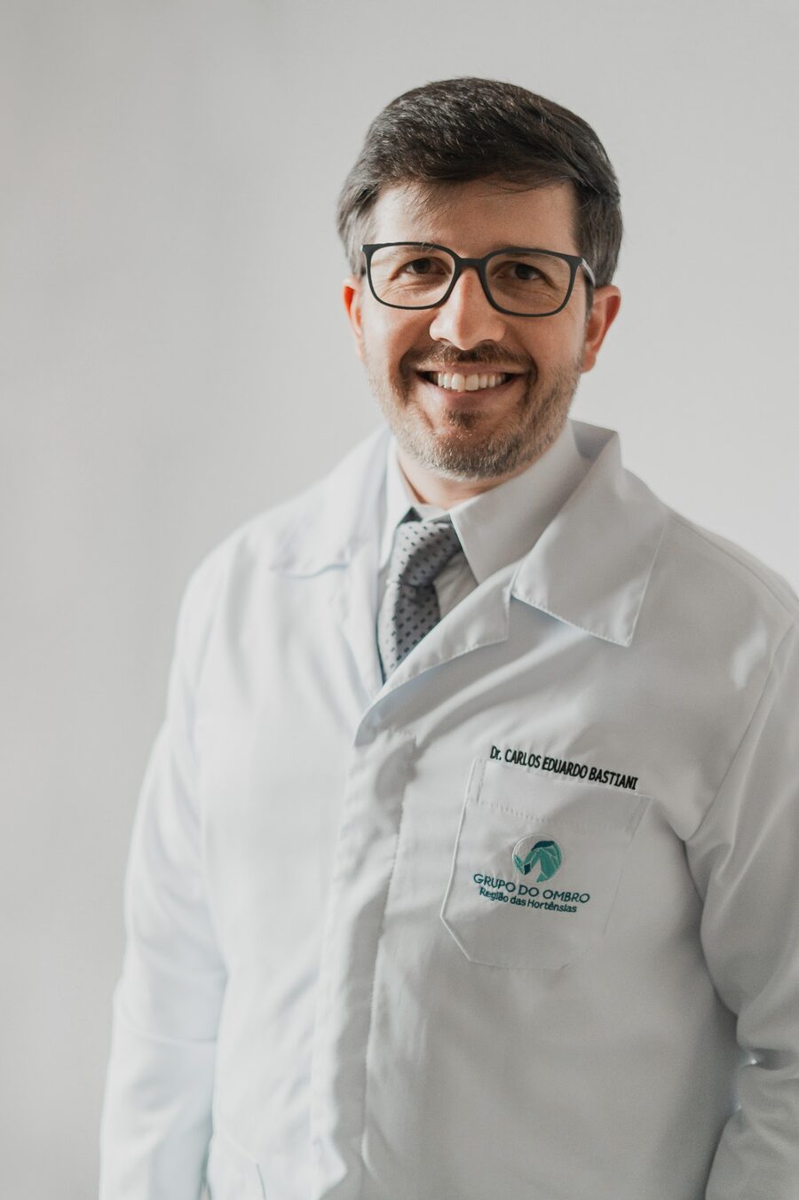Dr. Carlos Eduardo Bastiani, de jaleco branco, sorrindo